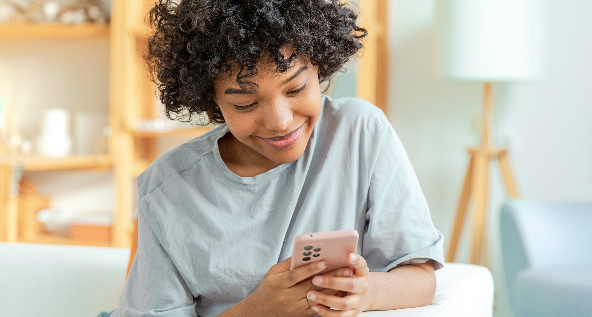 közeli fotó egy mosolygó személyről, aki mobiltelefont néz