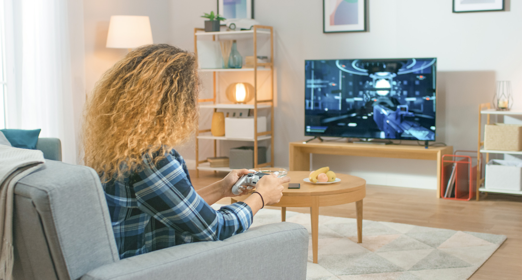 hosszú göndör hajú személy a nappaliban videojátékokat játszik a televízión